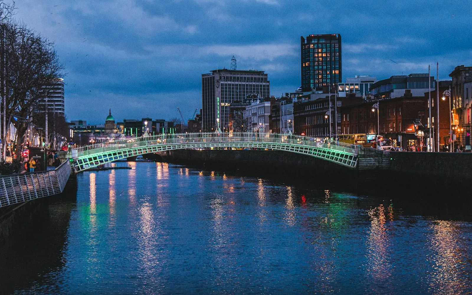 El Ha'penny Bridge iluminado sobre el río Liffey en Dublín, al atardecer