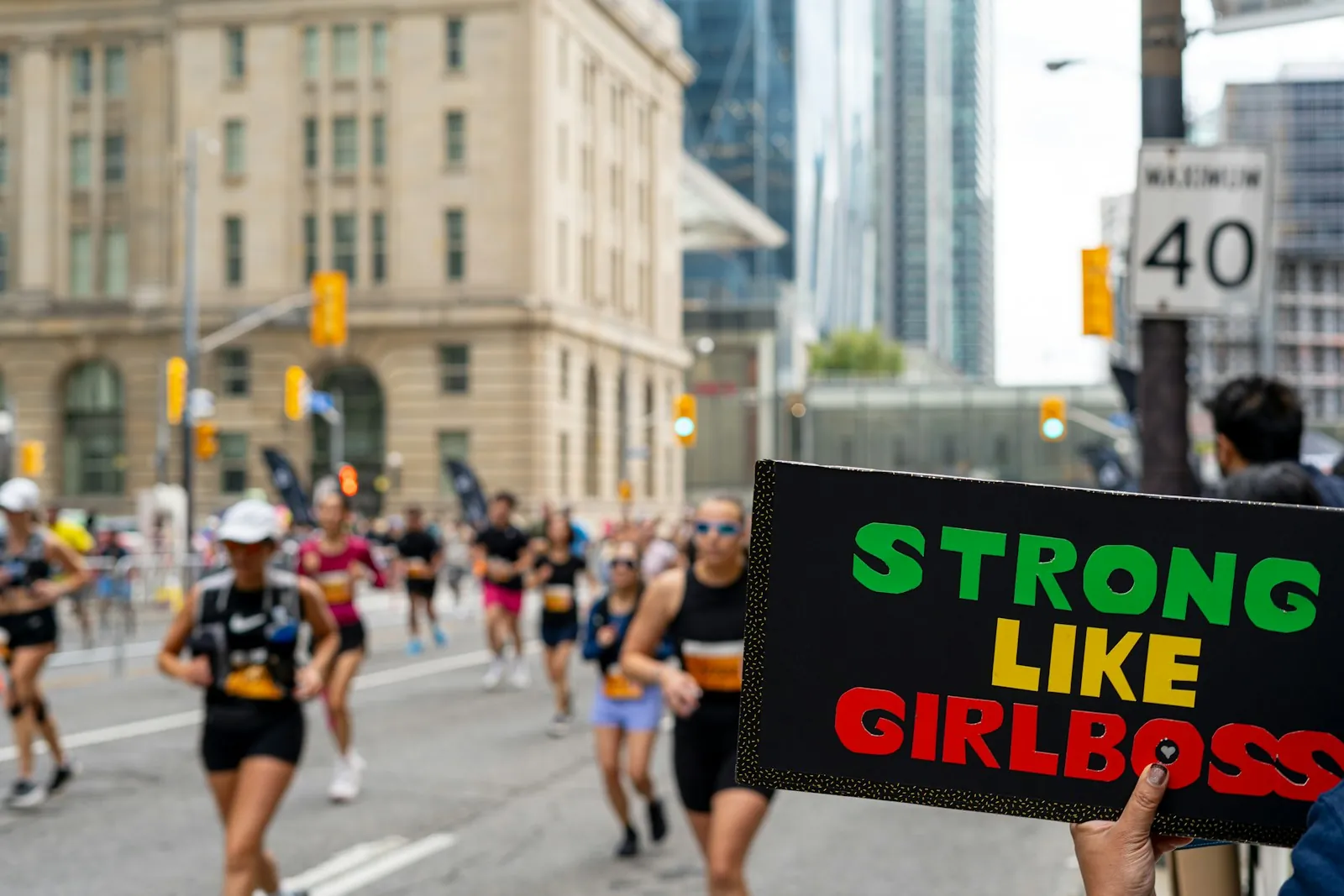 Futók egy „Strong like girlboss” tábla mellett